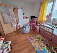 Children's room in a 3-room apartment with a bed, toys, and a colorful carpet.