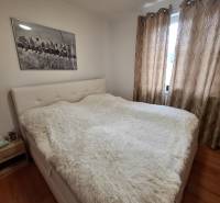 A bedroom in a 3-room apartment with a light bed, blackout curtains, and a painting on the wall.