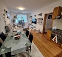 Kitchen corner and living room in a 3-room apartment with a table, sofa, and television.