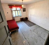 A simple room with a bed in a family house, wooden floors, curtains on the window.