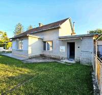 A family house in Kuzmice surrounded by a lawn and trees with a garage on the side.