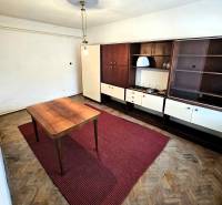 A room with a wooden table, a red carpet, and retro furniture in a family house.
