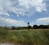 Natural scenery in Ľubotín with commercial land, sky with clouds and green vegetation.