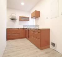 A small kitchen with wooden cabinets and a range hood suitable for a family house.