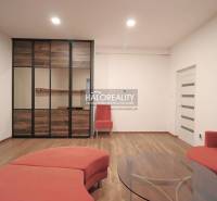 Living room in a family house with a red sofa, wooden floor, and glass table.