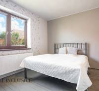 A bedroom in a family house with a metal bed and a large window with a view.