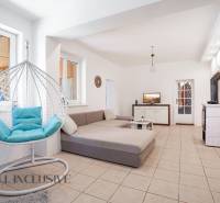 The interior of a family house with a comfortable sofa, a hanging chair, and a tiled stove.