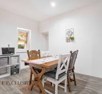 Dining room in a family house with a wooden table and chairs, white wall, and decoration.