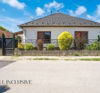 A family house in Tvrdošovce with a modern roof, landscaped garden, and wrought iron fence.