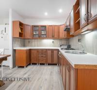 A kitchen in a family house with a light floor and wooden cabinets.
