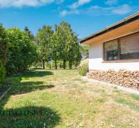 The garden of a family house in Tvrdošovce with a lawn, wood, and green trees.