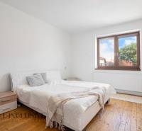 Bright bedroom in a family house with a white bed and wooden floor.