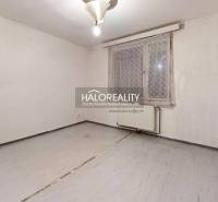 An empty room with light walls and floor and a radiator in a 3-room apartment.