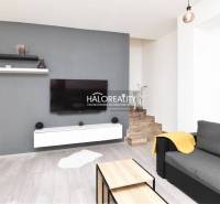 Living room in a family house with a TV on a grey wall, stairs by the wall.
