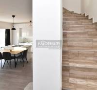 Dining area with staircase in a family house, wooden floors, light furnishings.