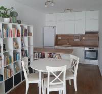 A kitchen in a 2-room apartment with a dining table, a bookshelf, and built-in appliances.