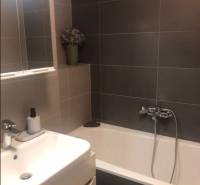 Bathroom in a 2-room apartment with a bathtub, sink, and mirror on the wall.