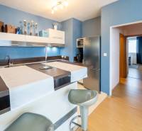A kitchen with a bar counter and stools in a 3-room apartment, blue walls and wooden floor.