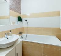 Bathroom in a 3-room apartment with a bathtub, sink, and mirror with wooden paneling.