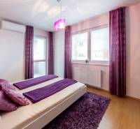 A bedroom in a 3-room apartment with purple accessories, a large bed, and air conditioning.