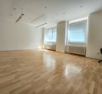 Spacious commercial spaces with wooden flooring and large windows with blinds.