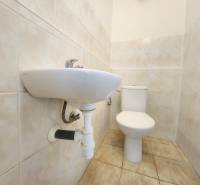 Bathroom with a toilet and sink, tiled with light tiles. Commercial premises.