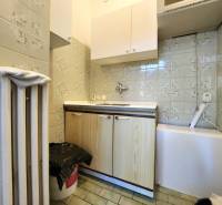 Kitchen corner with a sink, cabinets, and a heater in commercial premises.