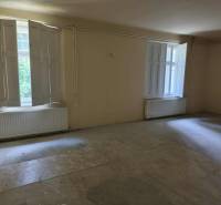 A spacious room with two large windows and radiators in a family house.