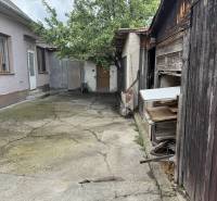 The courtyard of a family house in Dobrohošť with worn-out buildings and concrete paving.