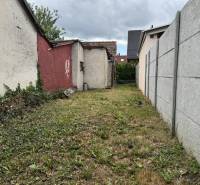 A narrow courtyard in Dobrohošť of a family house surrounded by walls with a grassy area.