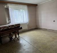 A room in a family house with a piano, an open window, and a curtain on the radiator.