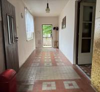 A hallway in a family house with older tiles and a window with a view.