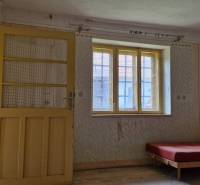 Interior of a family house with a bed, door, and window.