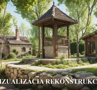 A family house made of stone and wood, surrounded by greenery and a pathway.