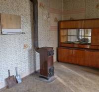 A room in a family house with a stove, an antique cabinet, and wallpaper on the walls.
