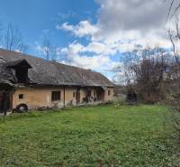 An old building and a family house surrounded by nature with an abandoned garden and lawn.