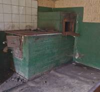 A traditional stove in the kitchen of a family house with tiles and old furniture.
