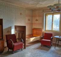 A room in a family house with antique furniture, armchairs, and wallpapered walls.