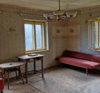 A room in a family house with old furniture and patterned wallpaper.