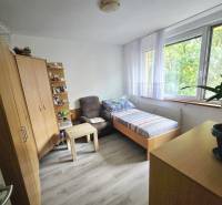 A room in a 2-room apartment with a bed, a cabinet, an armchair, and large windows.