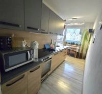 A kitchen in a 2-room apartment with dark cabinets, a microwave, and outdoor lighting.