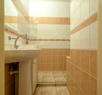 A bathroom with light tiles and a sink in a 2-room apartment.