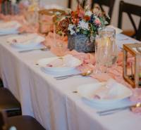 Tables set with decorations and flowers in dining areas, prepared for a festive event.