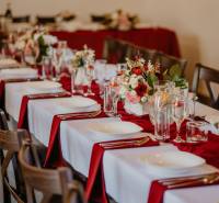 Festively set tables in dining areas with red napkins and floral arrangements.