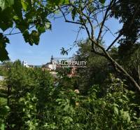 The view from the gardens in Nová Baňa, with a church and trees in the foreground.