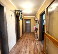 A hallway of a family house with a wooden floor and doors, furnished with coat racks.