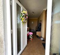 Entrance to a family house with a floral wreath on the door and tiles on the floor.