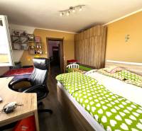 Children's room in a family house with wooden furniture, a bed, shelves, and a desk.