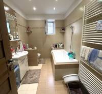 A bathroom in a family house with a bathtub, a sink, and a window.
