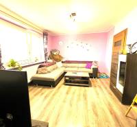 Living room in a family house with a corner sofa, decorations, and a window with flowers.